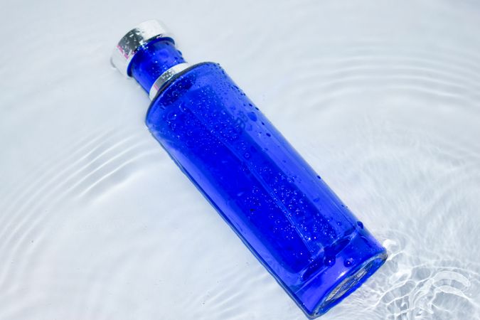 Blue perfume bottle laying in water