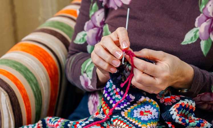 Hands of woman knitting a vintage wool quilt