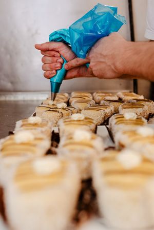Anonymous baker decorating pastry with cream