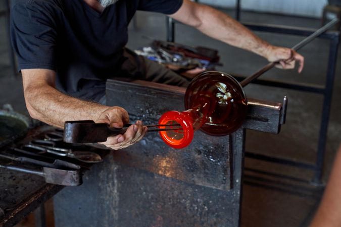 Faceless male glassblower manufacturing glass product