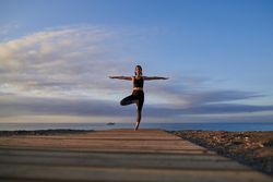 Fit woman practicing yoga on seashore