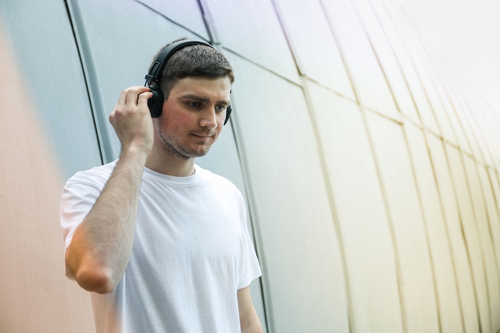 Young man in t-shirt listening to music in headphones