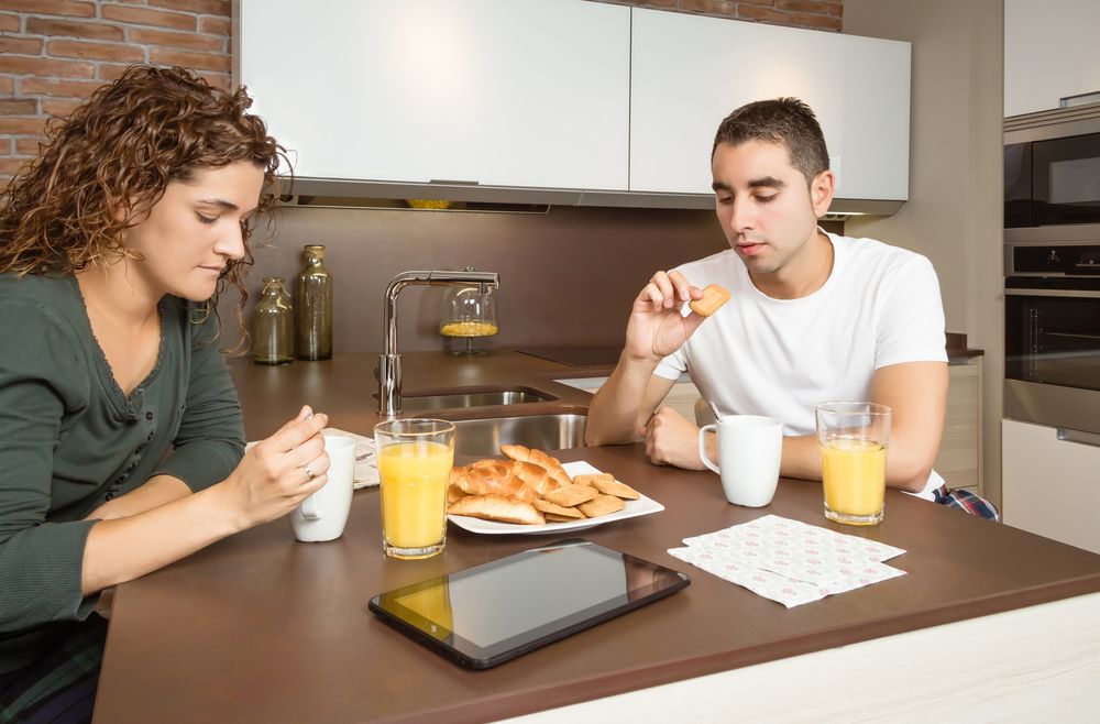 Couple eating pastries and drinking coffee at breakfast