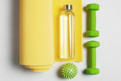 Colorful weights, yoga mat and water
