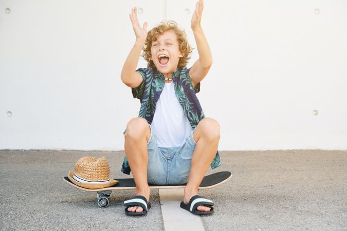 Cheerful boy sitting on skateboard
