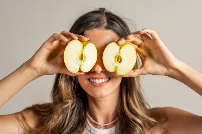 Playful Woman Holding Apple Slices in Front of Her Eyes - Happy woman playing with fruit