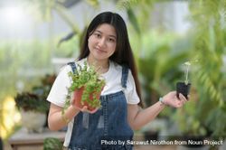 Asian female holding 2 pots of plants at work bY1Mjb