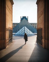 Back view of woman walking toward the Louvre museum in Paris, France bGgd2b