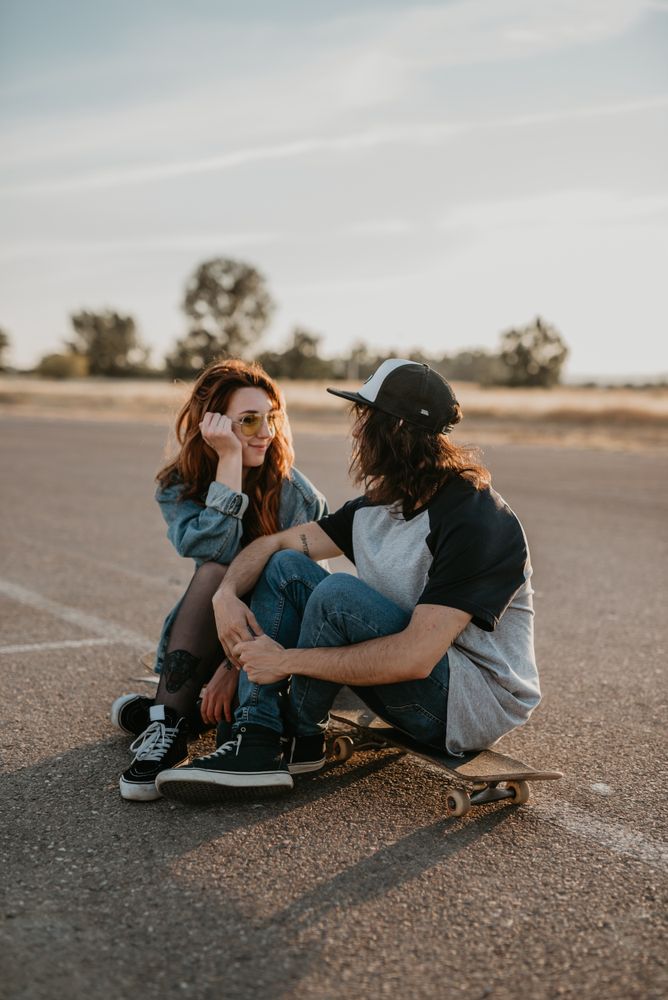 Skaters sitting on empty rural road chatting in sunlight