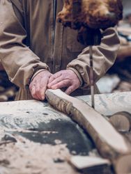 Unrecognizable carpenter cutting wooden piece