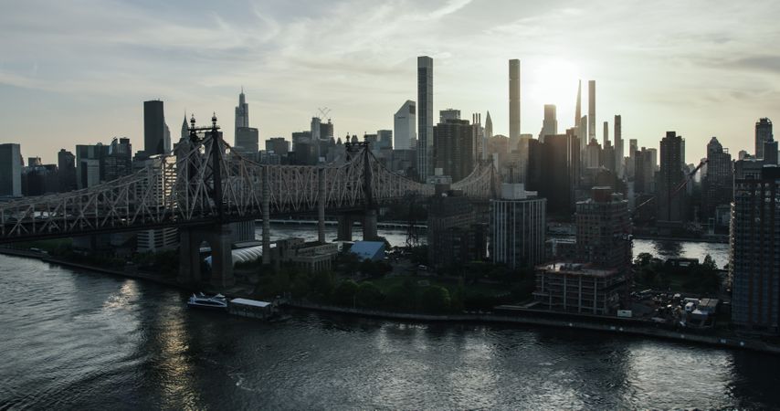 New York City Cityscape at Sunset. Aerial Shot from a Helicopter. Modern Skyscraper Buildings Shot Near Ed Koch Queensboro Bridge. Focus on Roosevelt Island and Engineering Details of the Bridge