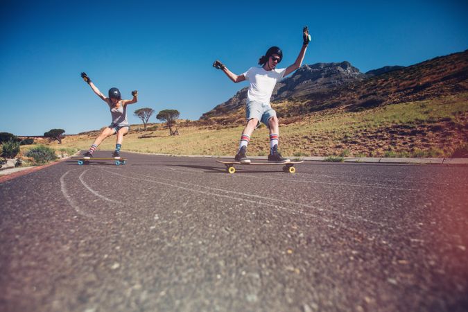 Young man and woman skateboarding on the road