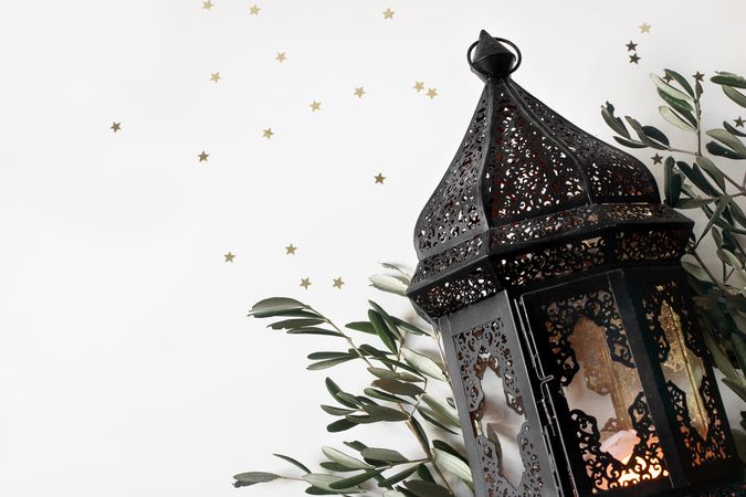 Glowing dark Moroccan, Arabic lantern and olive tree twigs isolated on table background.