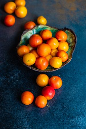 Bowl of orange plums on dark counter