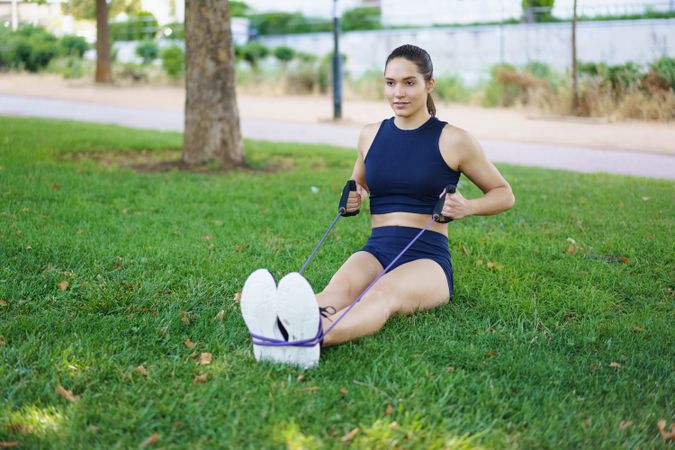 Woman working out arms with resistance band in park