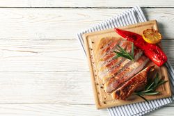 Board with fried steak on wooden background. Grilled food
