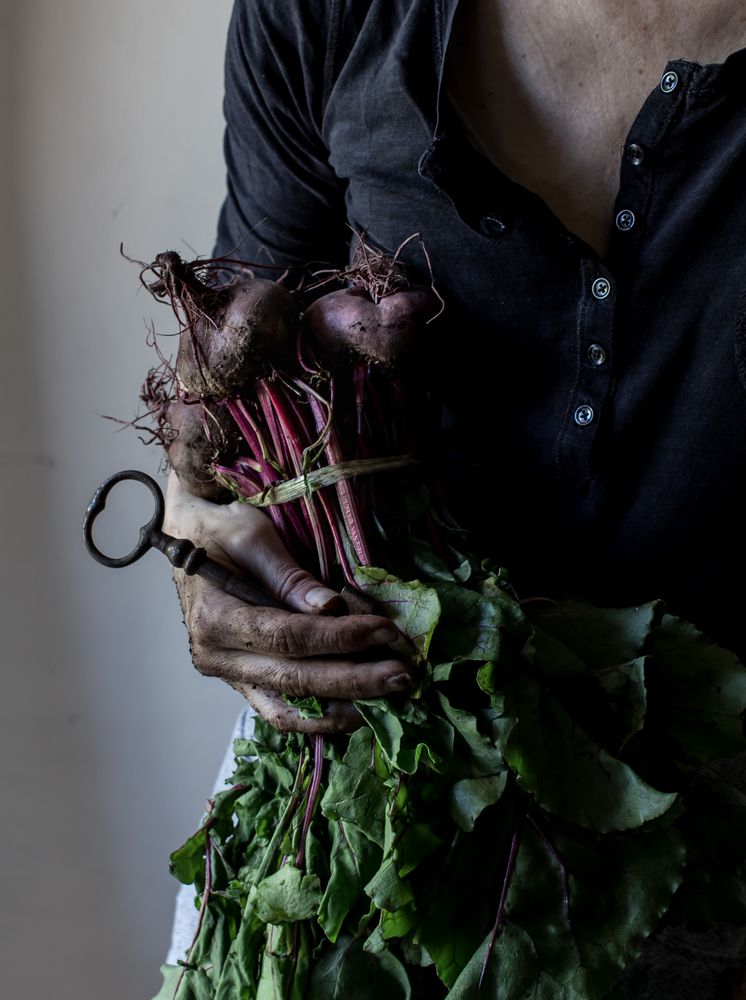 Faceless person with bunch of beetroots and key