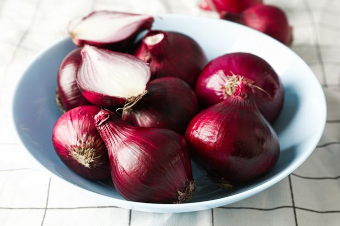 Plate with red onion on towel background, closeup