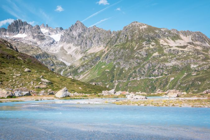 Azure water and mountains covered with greens under bright blue sky