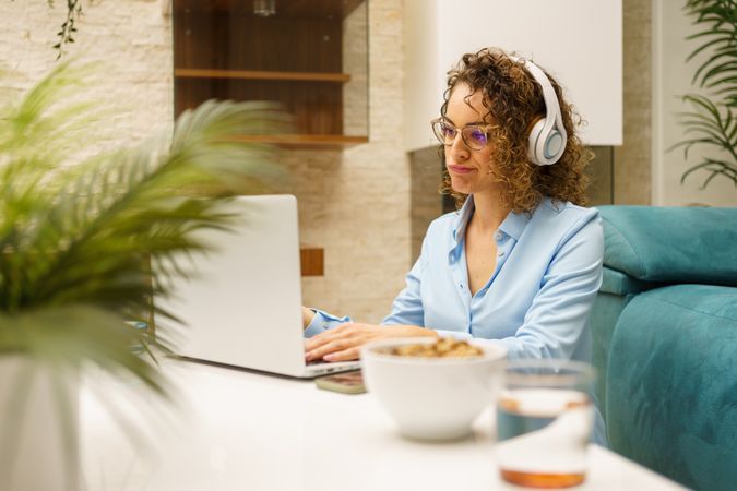 Woman working from home over breakfast in living room