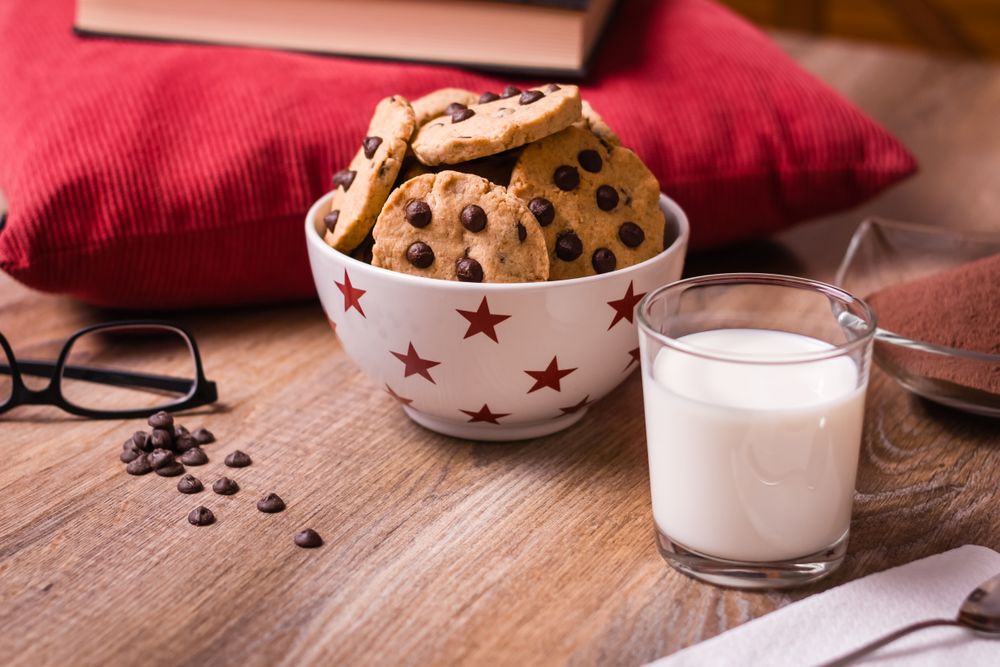 Chocolate chip cookies and milk on wood background