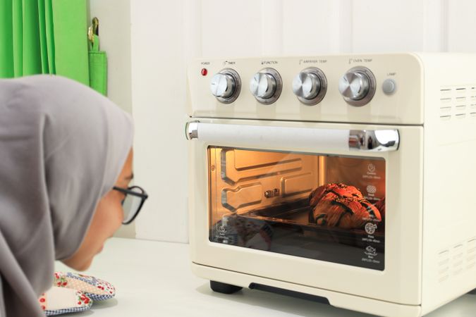 Asian Woman in Hijab Peeks into Oven, Baking Cropat or Ketupat Croisants