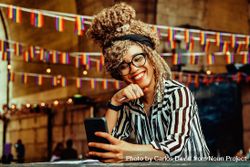 Black woman in stripe shirt smiling on video call in cafe bEZpA0