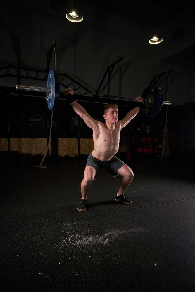 Strong man lifting barbell with weights in gym