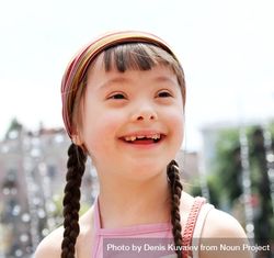 Portrait of a girl with Down syndrome with braids and a pink headband 5rLJdb
