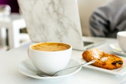 Coffee and croissant beside computer on a table 0LXPy0