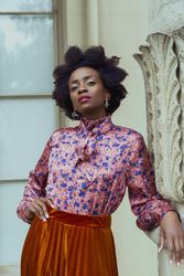 Woman in blue and pink floral top and brown skirt posing indoor