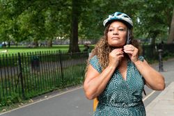 Black woman adjusting her helmet in city park 5zD6ob