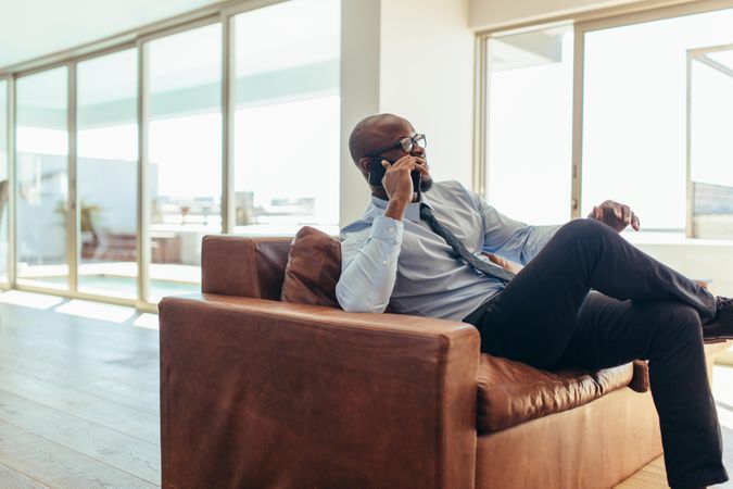 Businessman talking over mobile phone sitting on a lounge