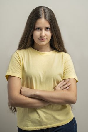 Confident young woman standing with folded arms showing natural skin texture in portrait