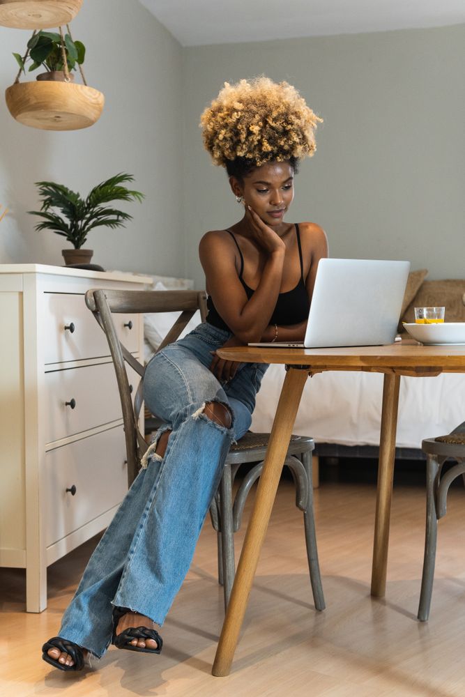 Black woman with laptop sitting on chair during breakfast