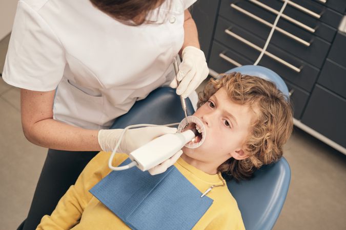 Crop dentist using intraoral scanner to preteen boy