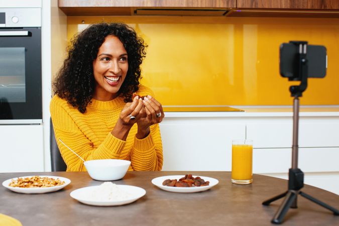 Woman in colorful kitchen live-streaming her breakfast