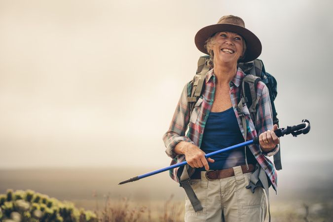 Portrait of a smiling woman hiker walking holding her hiking pole