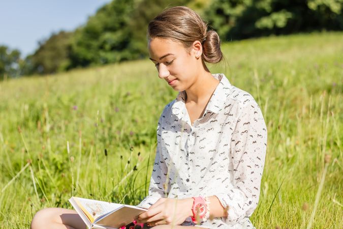 young student reading a book in the park