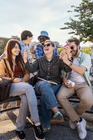 Happy diverse friends having fun outdoors with reusable water bottles.