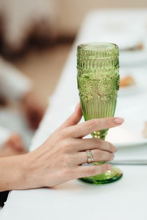 Person holding green glass at a table