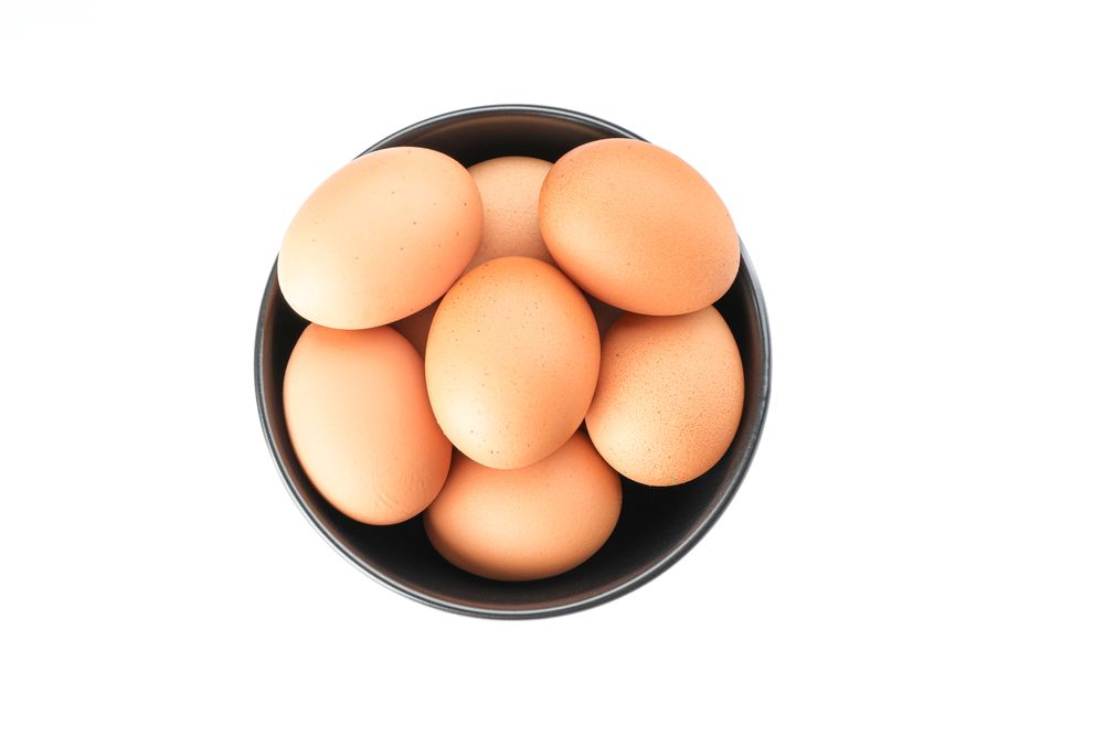Brown chicken eggs in bowl isolated on plain background, top view