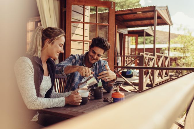 Couple sitting outside a holiday cabin and having coffee