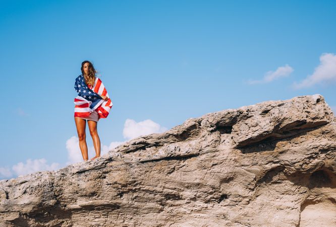 Peaceful patriotic female traveler enjoying in vacation at rocks