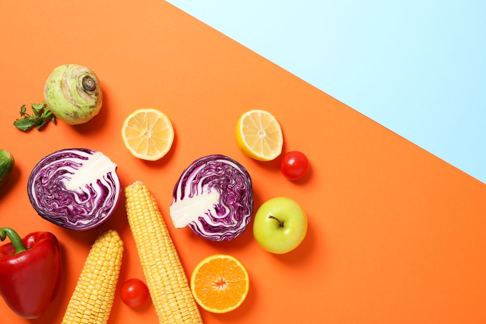 Different vegetables and fruits on two tone background, copy space