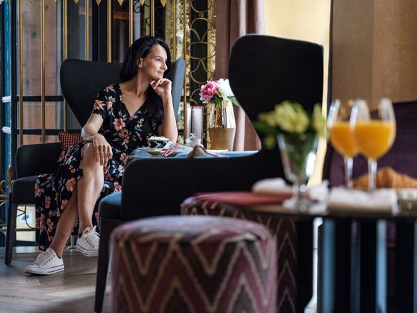 Trendy woman resting in armchair in cafe in hotel
