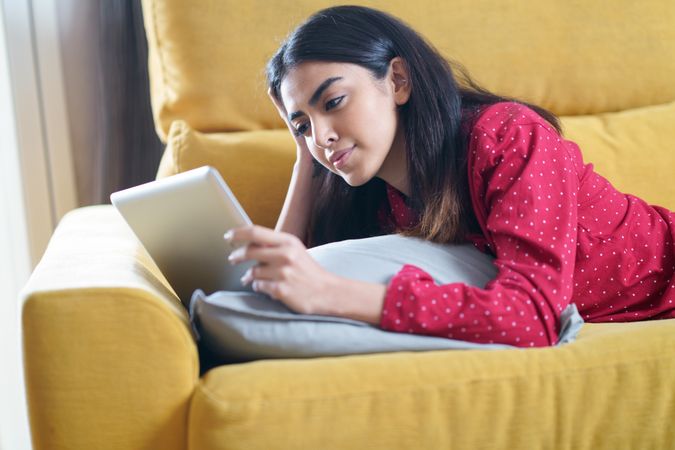 Woman relaxing at home and reading something on a tablet