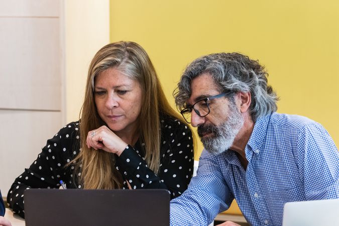Serious coworkers working on laptop in office