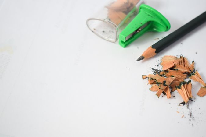 Pencil laying on table with shavings & sharpener with space for text