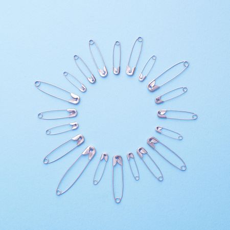 Safety pins in a circle shape over blue background